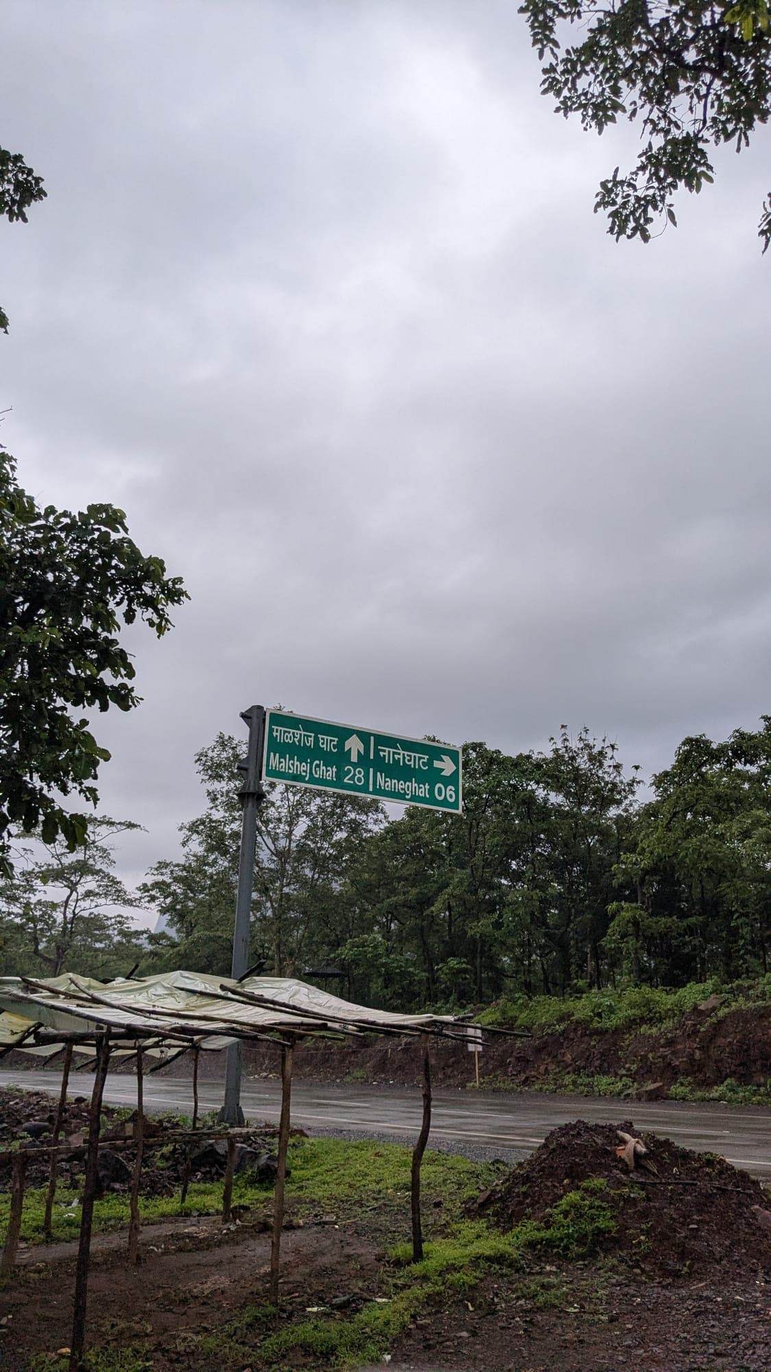 Highway sign at dusk reading Malshej Ghat 28 and Naneghat 6